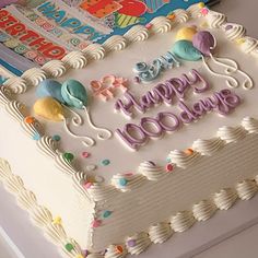 a birthday cake with the words happy 100th written on it, surrounded by books and balloons