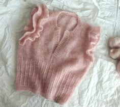 a pink sweater laying on top of a white sheet