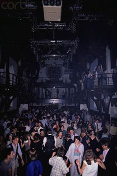 a large group of people standing around each other in front of a stage at night