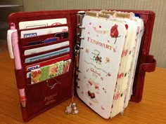 an open red wallet sitting on top of a wooden table next to a note book