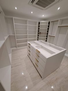 an empty walk in closet with white cabinets and shelves on the wall, along with marble flooring