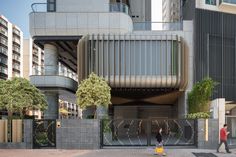 two people are walking in front of a building with an open gate on the street