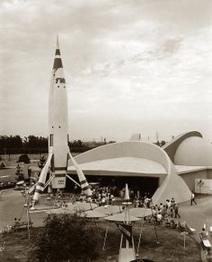 an old black and white photo of people in front of a building with a rocket on it