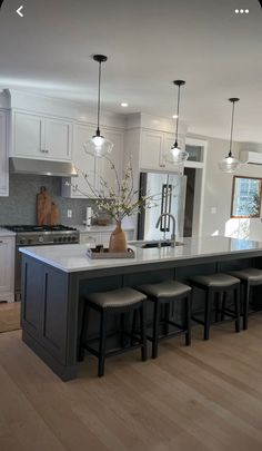 a kitchen with an island and four stools in front of the countertop area