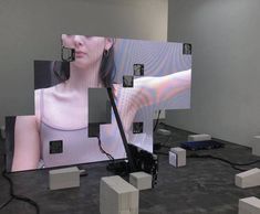 an image of a woman's face is projected on the wall behind cubes