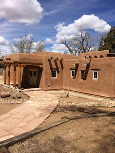 an adobe - style house is shown in the middle of a dirt lot with trees and rocks