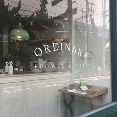 the window of a flower and cafe with an old wooden table in front of it