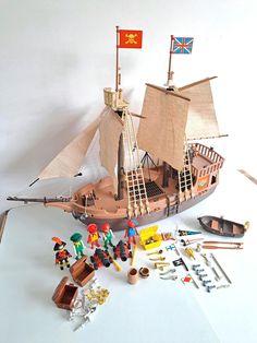 a wooden pirate ship with figures and accessories on a white surface next to other toys