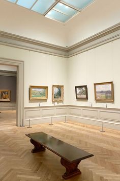 an empty room with paintings on the wall and wooden benches in front of each other