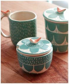 two tea cups sitting next to each other on top of a wooden table with one cup in the middle