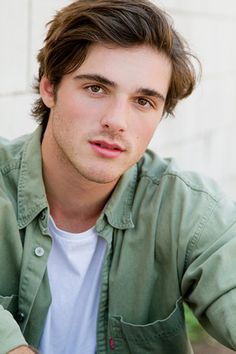 a close up of a person wearing a green shirt and looking at the camera with a serious look on his face