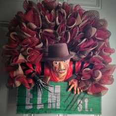 a creepy scarecrow hanging from the side of a door with red and green decorations