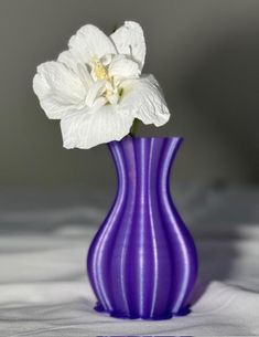 a purple vase with a white flower in it