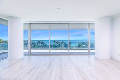 an empty room with large windows overlooking the ocean