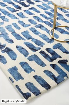 a blue and white rug with an abstract design on the bottom, next to a glass table