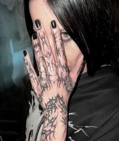 a woman with black nails and tattoos covering her face