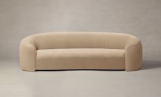 a beige couch sitting on top of a white floor next to a wall with a gray background