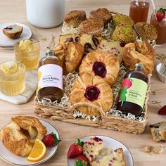 a basket filled with croissants, muffins and jam on plates