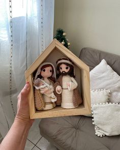 a person holding up a small nativity scene