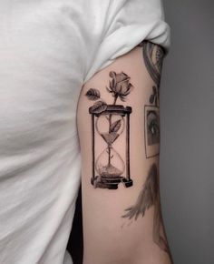 a woman's arm with an hourglass and rose tattoo on it