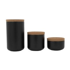 three black containers with cork lids on white background