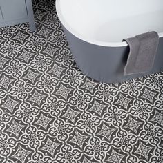 a bath tub sitting next to a white sink in a bathroom on top of a tiled floor