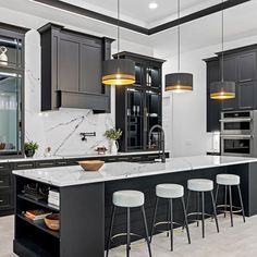 a large kitchen with black cabinets and white counter tops, an island in the middle is surrounded by stools