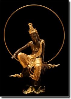 a golden statue sitting in the middle of a circle on top of a black surface