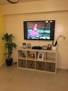 a flat screen tv sitting on top of a white shelf next to a potted plant