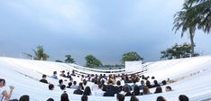 a group of people sitting on top of white seats next to each other in front of palm trees