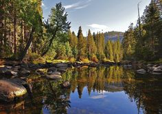 a lake surrounded by lots of trees and rocks