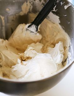 a metal bowl filled with cream on top of a table