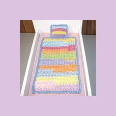 a crocheted bed in a box with a blanket and pillow on top of it