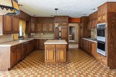 an empty kitchen with wooden cabinets and tile flooring in the middle of the room