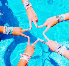 four people are standing in the middle of a pool making a star with their hands