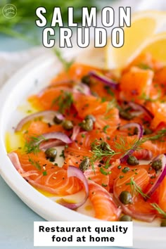 salmon and onions on a white plate with lemon wedges next to the caption reads salmon crudo restaurant quality food at home