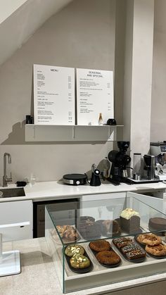 a display case with donuts and pastries on it in a kitchen area next to a coffee machine