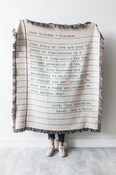 a person holding up a blanket with writing on it