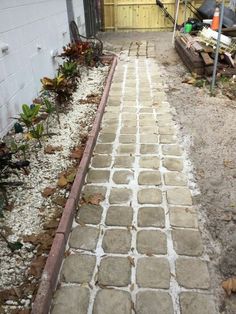 a walkway made out of cement next to a building with a wooden fence in the background