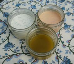 three jars filled with liquid sitting on top of a flowered table cloth next to each other