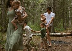 a group of people in the woods playing with each other and holding onto one another