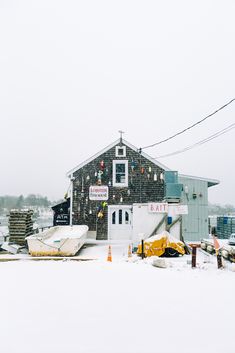 a boat is parked in front of a building on the snow covered ground with other boats and construction equipment around it