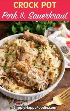 a white bowl filled with pork and sauerkraut on top of a wooden table