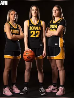 three female basketball players in black and yellow uniforms with their arms crossed, standing next to each other