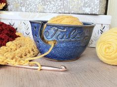 two balls of yarn sit next to a crochet hook and knitting needles on a table