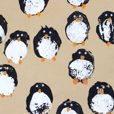 a group of penguins painted with black and white paint on brown paper, sitting next to each other