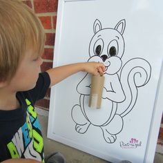 a young boy holding a roll of toilet paper in front of a drawing of a squirrel