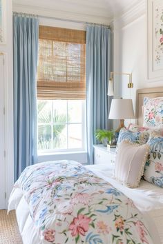 a bedroom with floral bedding and blue drapes on the window sill,