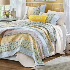 a bed with blue and yellow quilts on it