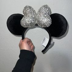 a person is holding up a mickey mouse ears headband with silver sequins